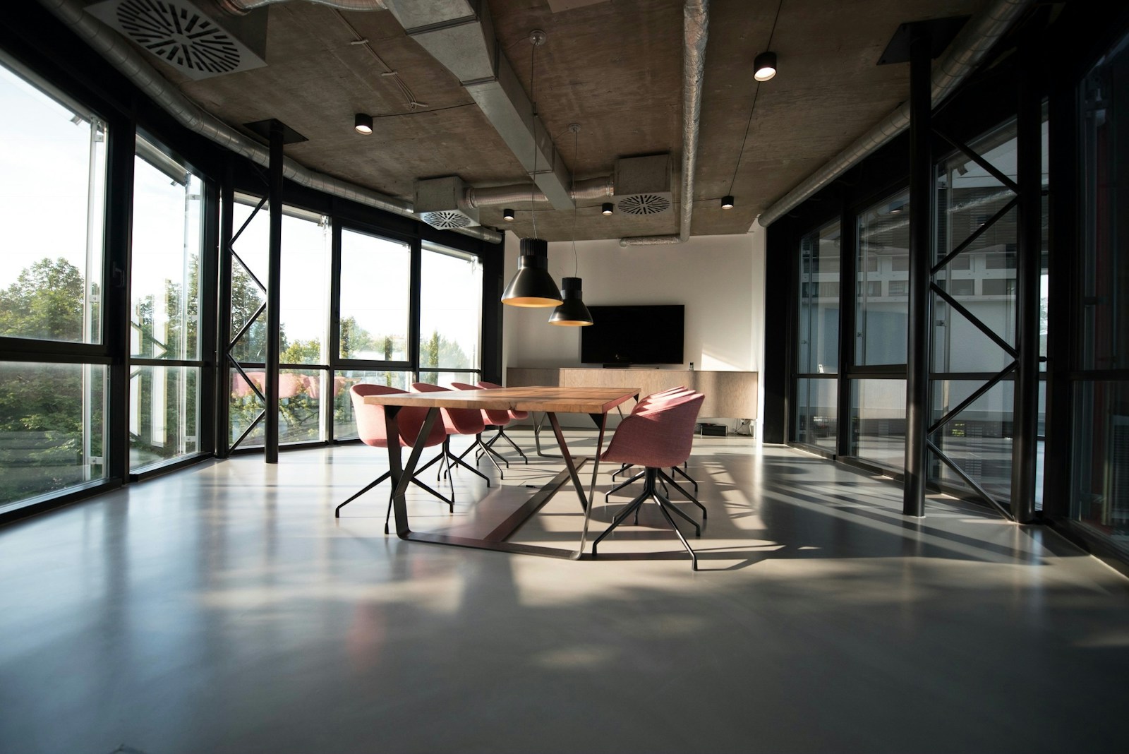 Afternoon light across a quiet meeting room with a long wooden table.