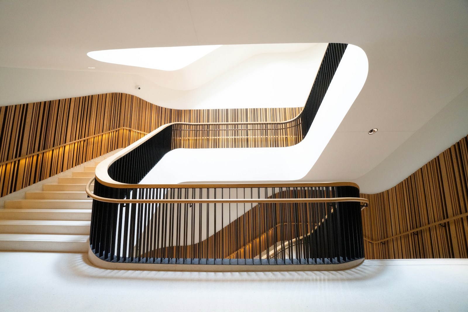 A sweeping staircase framed by warm wood and curved white walls.
