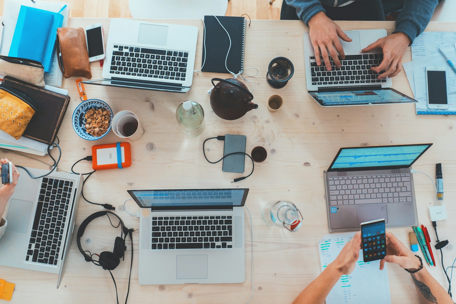 An overhead view of people working around a shared table with laptops and notebooks.